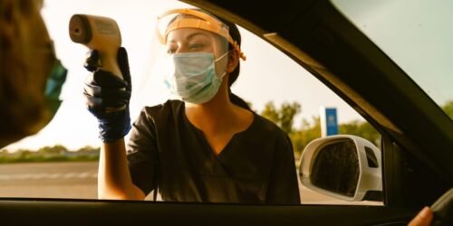 black-health-worker-measuring-temperature-of-woman-in-car-scaled-1.jpg